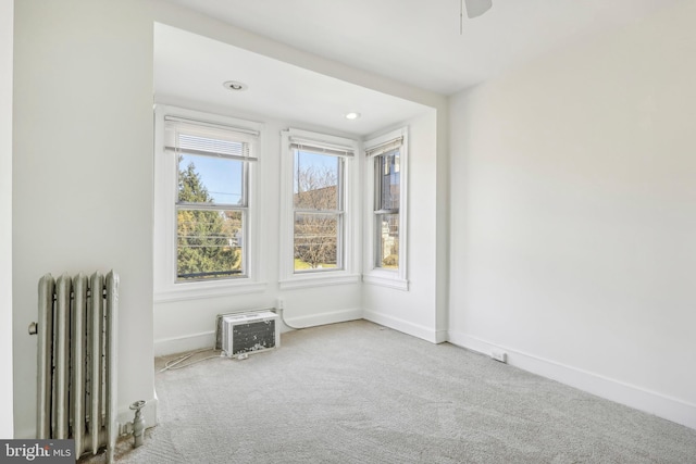 unfurnished room featuring radiator heating unit and light colored carpet