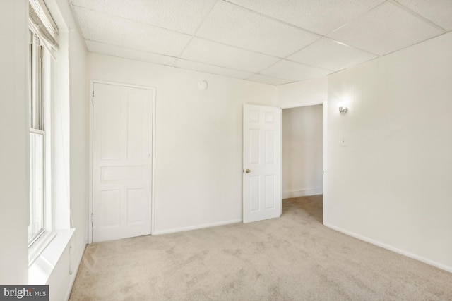 empty room featuring light carpet and a drop ceiling