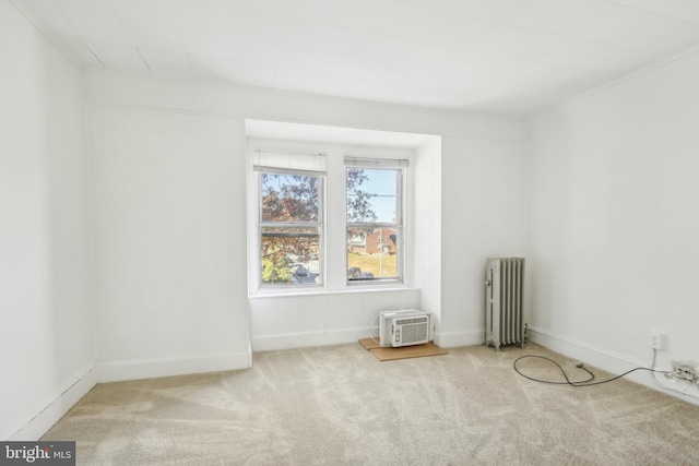 empty room with radiator heating unit, a wall unit AC, and light colored carpet