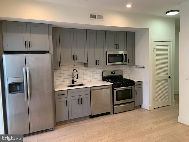 kitchen featuring appliances with stainless steel finishes, gray cabinets, light hardwood / wood-style flooring, and sink