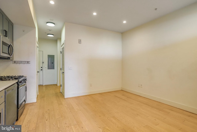 kitchen with light wood-type flooring, stainless steel appliances, and electric panel