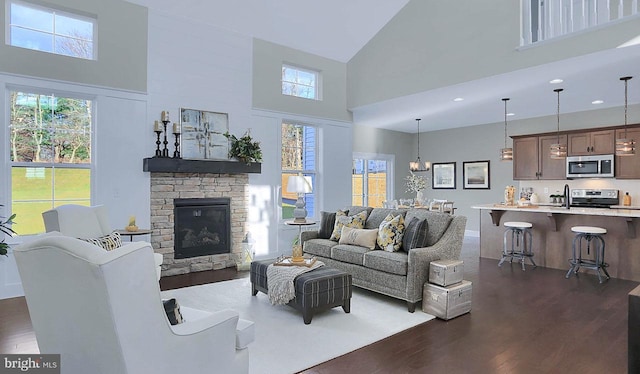 living room with dark wood-style floors, high vaulted ceiling, and a stone fireplace