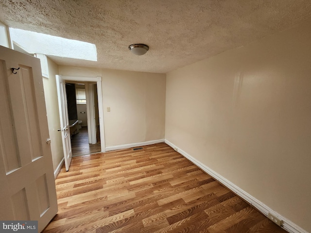 502 Brunswick St, Baltimore, MD 21223 - unfurnished room with a textured ceiling, light wood-type flooring, a skylight, and baseboards