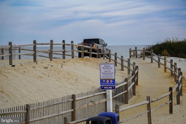 view of dock featuring a water view and a beach view