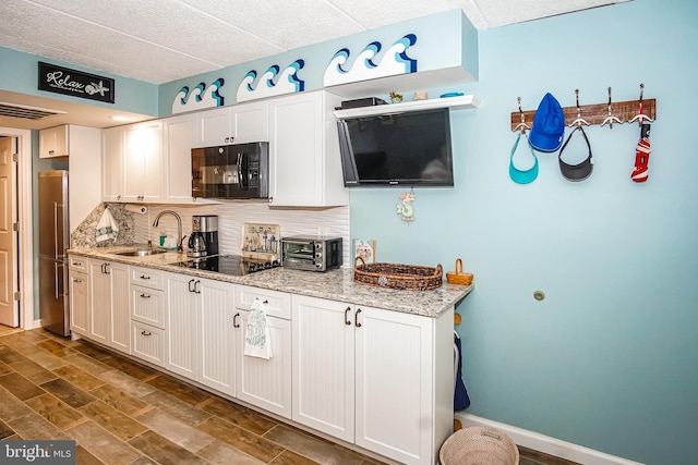 kitchen featuring white cabinetry, sink, black appliances, and light stone counters