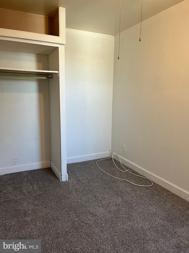 unfurnished bedroom featuring dark colored carpet and a closet