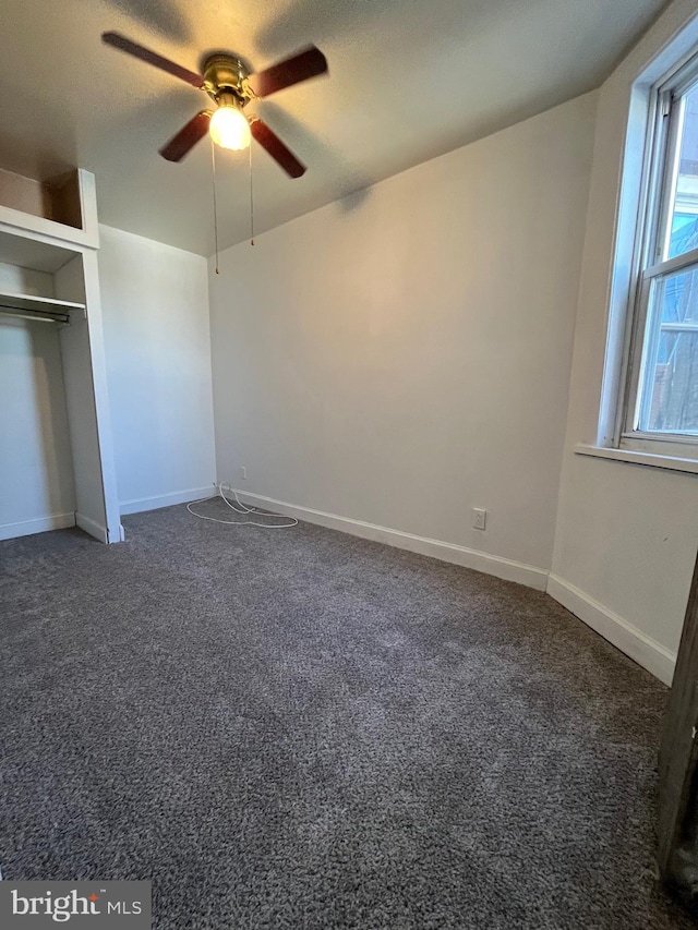 unfurnished bedroom featuring dark colored carpet, ceiling fan, a textured ceiling, and a closet