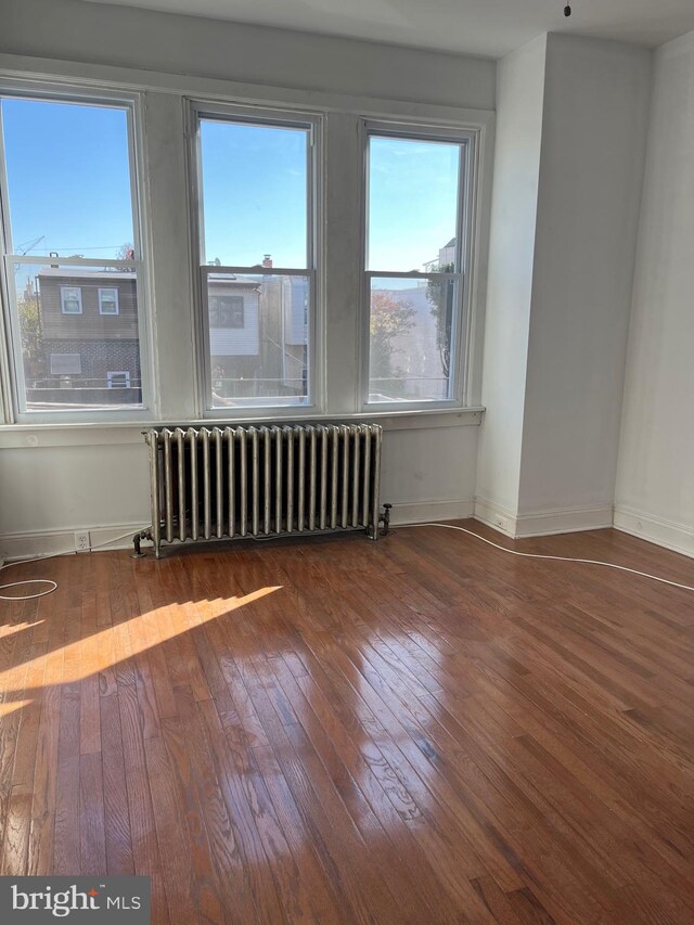 empty room featuring dark hardwood / wood-style flooring and radiator