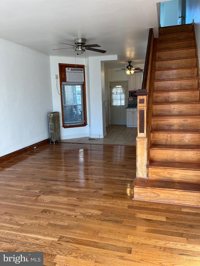 unfurnished living room with ceiling fan, wood-type flooring, radiator heating unit, and a wall mounted AC