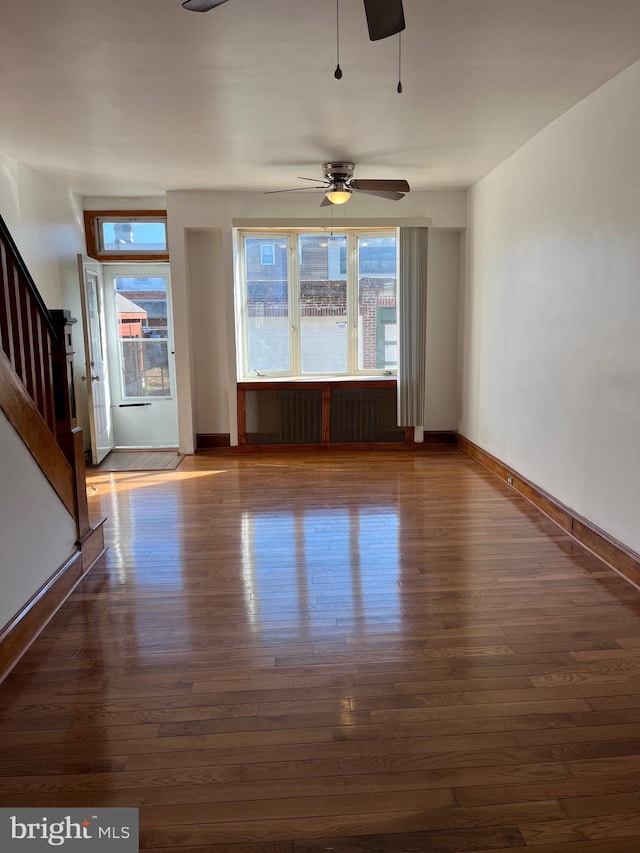 unfurnished living room with dark hardwood / wood-style floors and ceiling fan