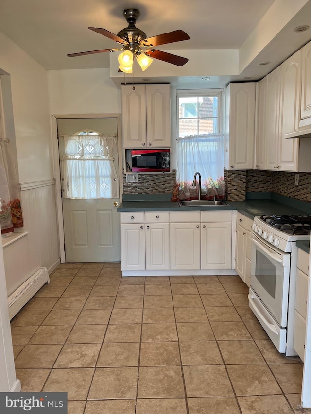 3358 Livingston St, Philadelphia, PA 19134 - kitchen featuring a sink, white gas range, a baseboard heating unit, plenty of natural light, and a wainscoted wall