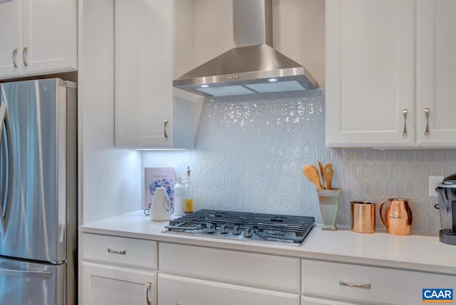 kitchen with white cabinets, wall chimney exhaust hood, decorative backsplash, and appliances with stainless steel finishes