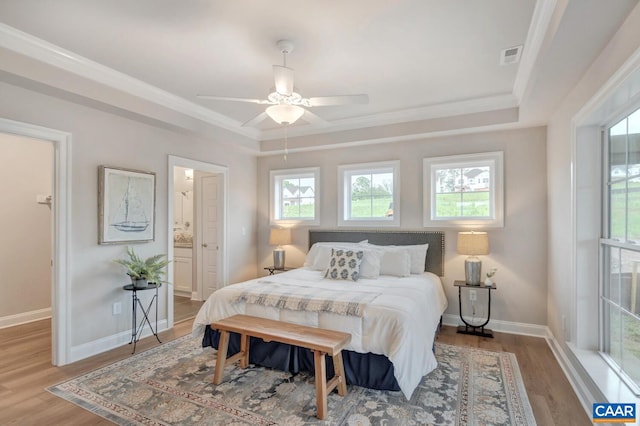 bedroom with light wood-type flooring, ensuite bath, multiple windows, and ceiling fan