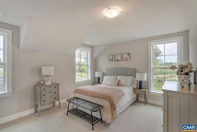 bedroom featuring multiple windows, light colored carpet, and lofted ceiling