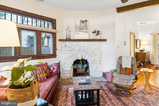 living room featuring beam ceiling, a fireplace, and wood-type flooring