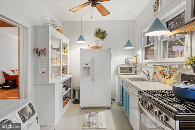 kitchen featuring sink, hanging light fixtures, light hardwood / wood-style flooring, white cabinets, and appliances with stainless steel finishes