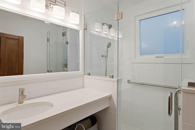 bathroom with a shower with shower door and sink