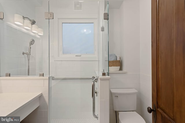 bathroom featuring vanity, toilet, tile walls, and walk in shower