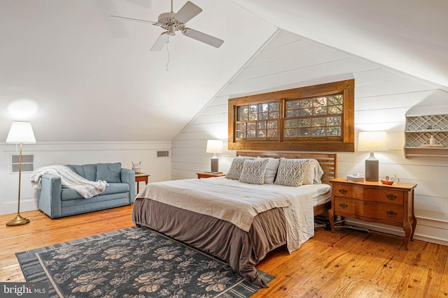 bedroom with multiple windows, ceiling fan, hardwood / wood-style floors, and vaulted ceiling