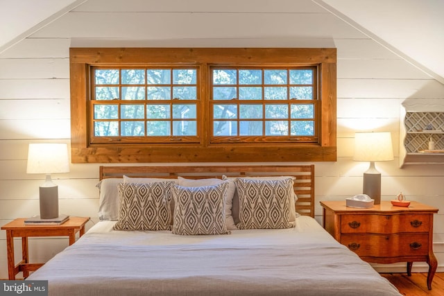 bedroom featuring hardwood / wood-style floors, multiple windows, and wooden walls