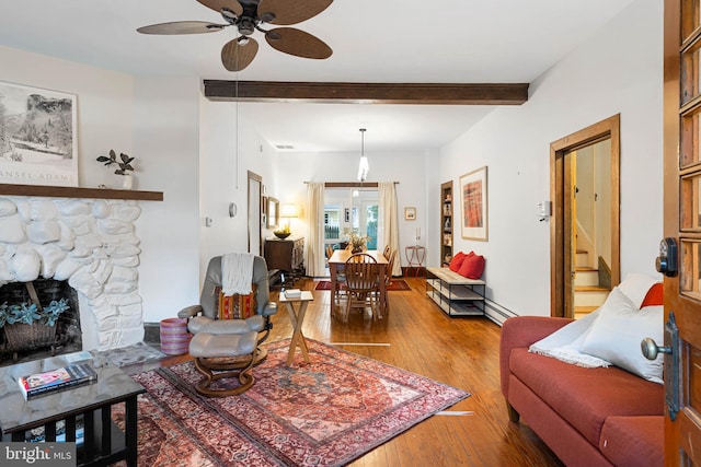 living room with beam ceiling, ceiling fan, baseboard heating, hardwood / wood-style floors, and a fireplace