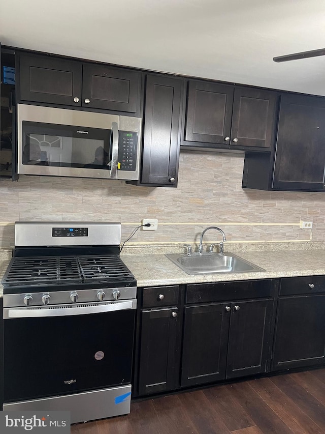 kitchen with sink, dark wood-type flooring, appliances with stainless steel finishes, and tasteful backsplash