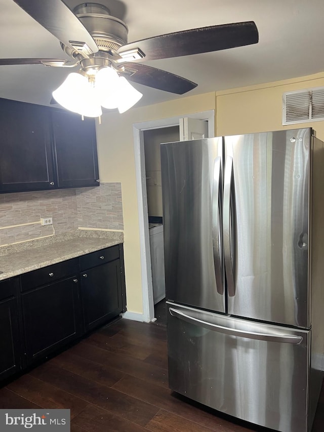 kitchen with ceiling fan, light stone countertops, tasteful backsplash, dark hardwood / wood-style flooring, and stainless steel fridge