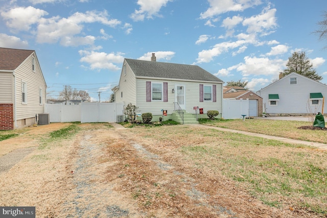 bungalow-style house with central air condition unit and a front yard