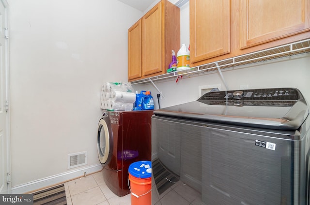 laundry area with cabinets, light tile patterned floors, and washer and dryer