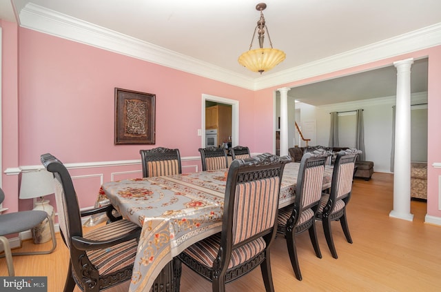 dining room featuring ornate columns, crown molding, and light hardwood / wood-style floors