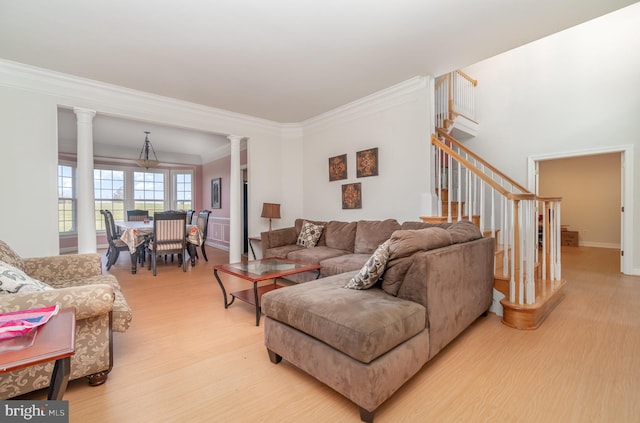 living room featuring light wood-type flooring, ornamental molding, and ornate columns