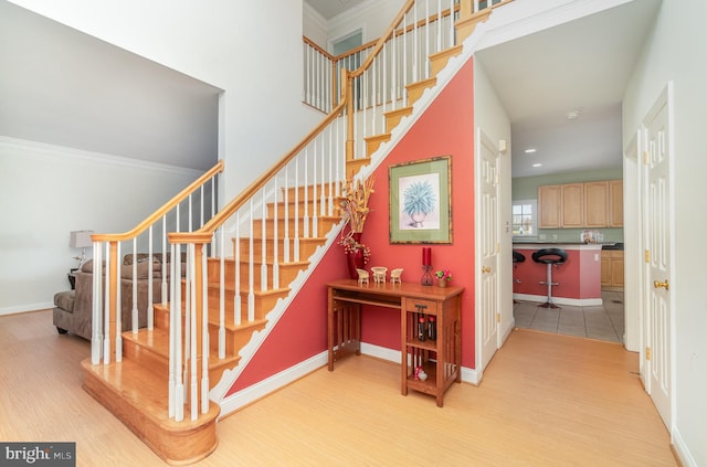 stairs featuring wood-type flooring and ornamental molding