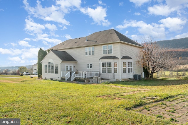 back of property featuring a lawn, cooling unit, and a deck