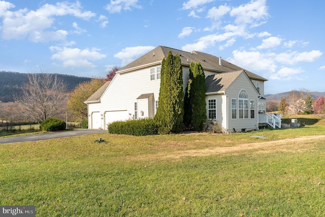 view of side of property with a lawn, a mountain view, and a garage