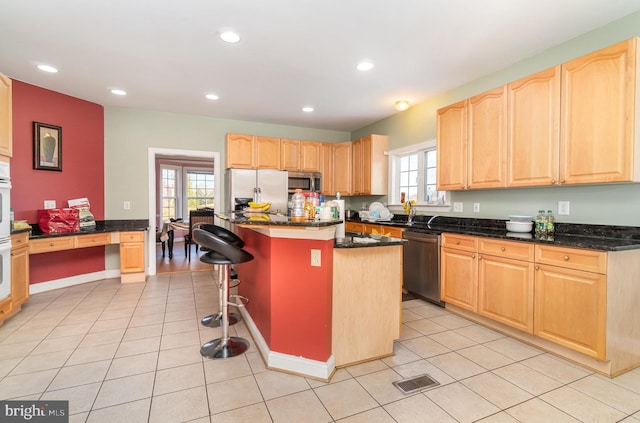 kitchen featuring appliances with stainless steel finishes, a center island, a wealth of natural light, and a breakfast bar area