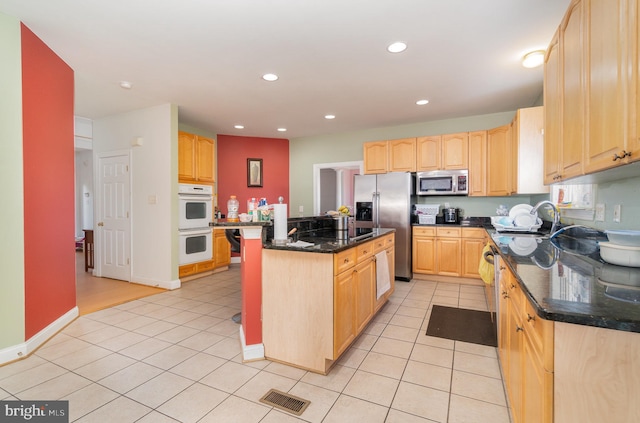 kitchen featuring light brown cabinets, dark stone counters, sink, a kitchen island, and stainless steel appliances