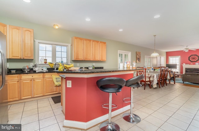 kitchen with ceiling fan, a kitchen island, decorative light fixtures, a kitchen bar, and light tile patterned floors