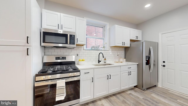 kitchen featuring white cabinetry, appliances with stainless steel finishes, backsplash, sink, and light hardwood / wood-style floors