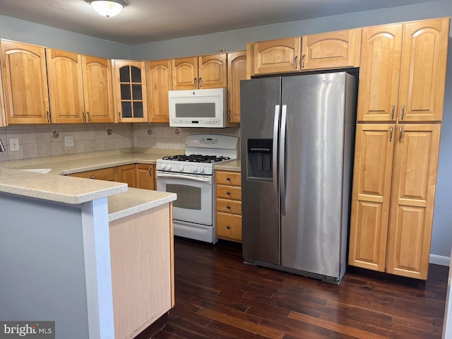 kitchen featuring dark hardwood / wood-style flooring, kitchen peninsula, white appliances, and decorative backsplash