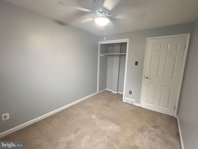 unfurnished bedroom featuring ceiling fan, light carpet, and a closet