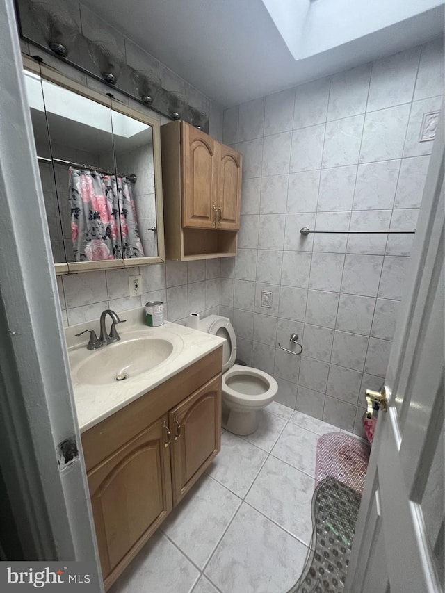 bathroom with tasteful backsplash, tile walls, vanity, tile patterned flooring, and a skylight