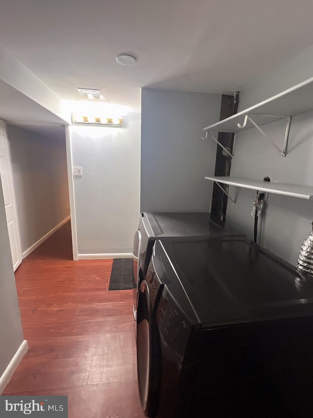 clothes washing area with wood-type flooring and washer and clothes dryer