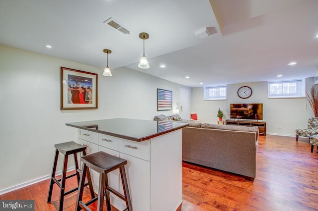 kitchen featuring a center island, hardwood / wood-style floors, white cabinets, and hanging light fixtures