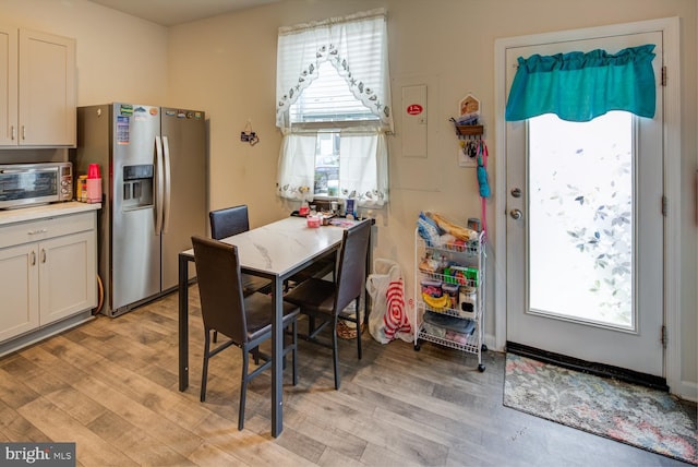 kitchen with white cabinets, light wood-type flooring, and stainless steel refrigerator with ice dispenser