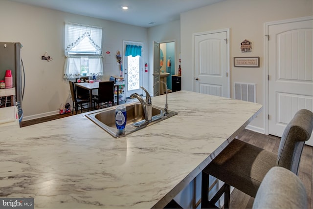 kitchen featuring a breakfast bar, dark wood-type flooring, and sink