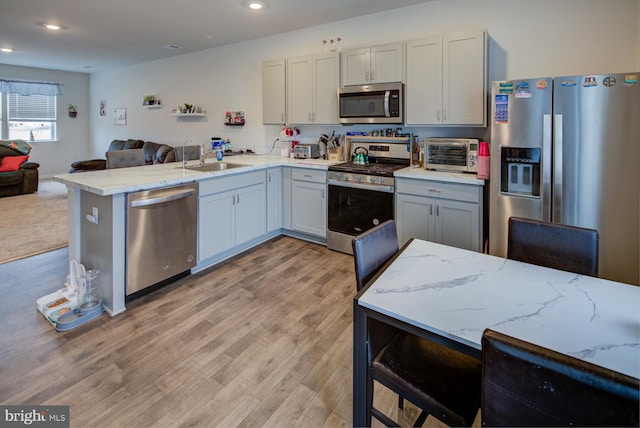 kitchen featuring kitchen peninsula, light hardwood / wood-style flooring, and appliances with stainless steel finishes