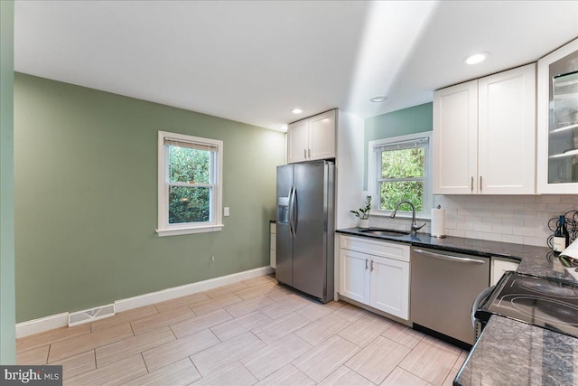 kitchen with appliances with stainless steel finishes, white cabinetry, a healthy amount of sunlight, and sink