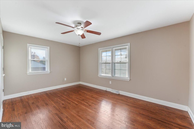 empty room with a wealth of natural light, dark hardwood / wood-style flooring, and ceiling fan