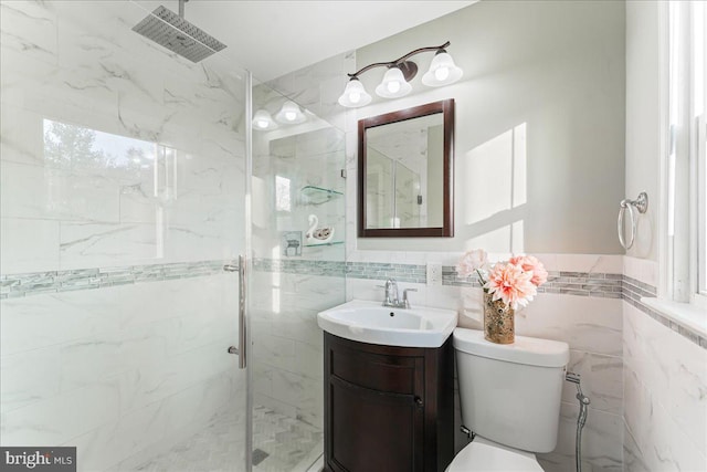 bathroom featuring vanity, a shower with door, toilet, and tile walls