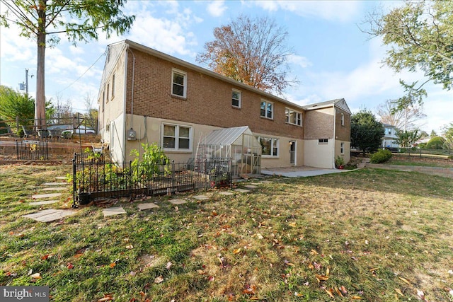 rear view of house with a lawn and a patio